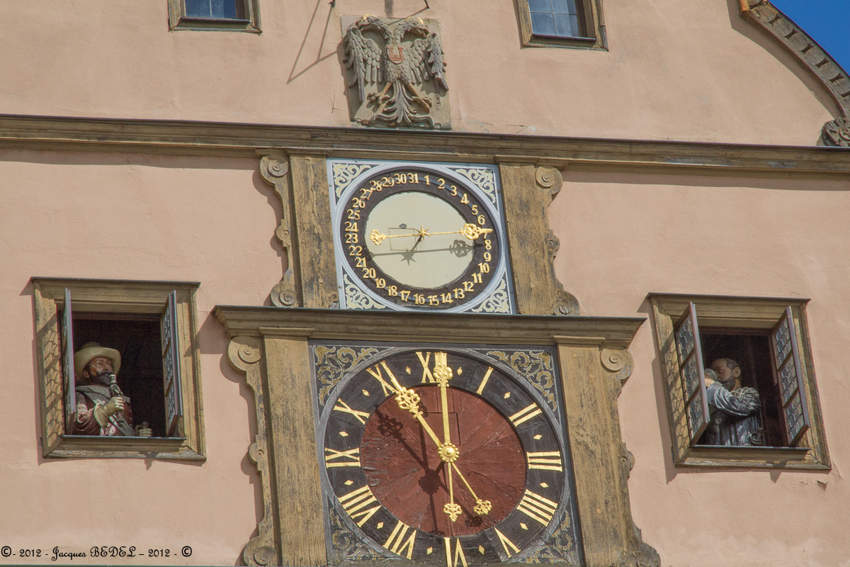Rothenburg ob der Tauber : La célèbre horloge sur la place du marché  illustre la légendaire histoire de la Rasade du Bourgmestre :  Le général Tilly dans un moment d'humeur  promit d'épargner la ville si un notable parvenait à vider d'un trait un hanap de 3 litres de vin. L'ancien bourgmestre Nusch réussit cet exploit et sauva alors sa ville.